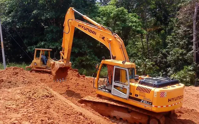 Excavadora moviendo tierra roja en una ladera